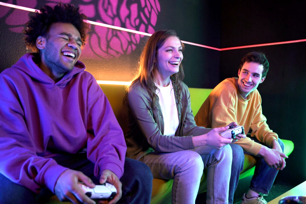 Tres personas juegan con un PlayStation 5 dentro de un local.