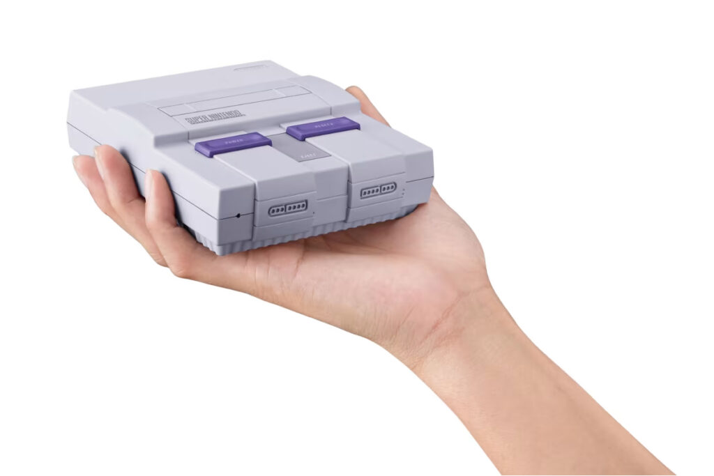 Una mano sostiene la consola de videojuegos SNES Classic Edition.