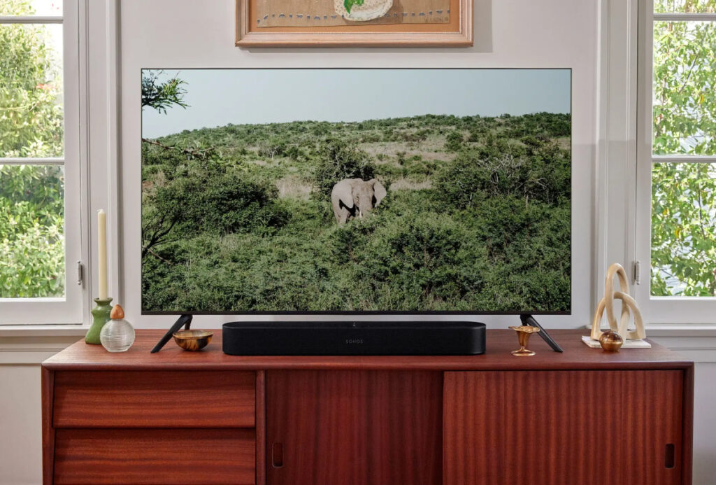 La barra de sonido Sonos Beam colocada en un mueble junto con un televisor.