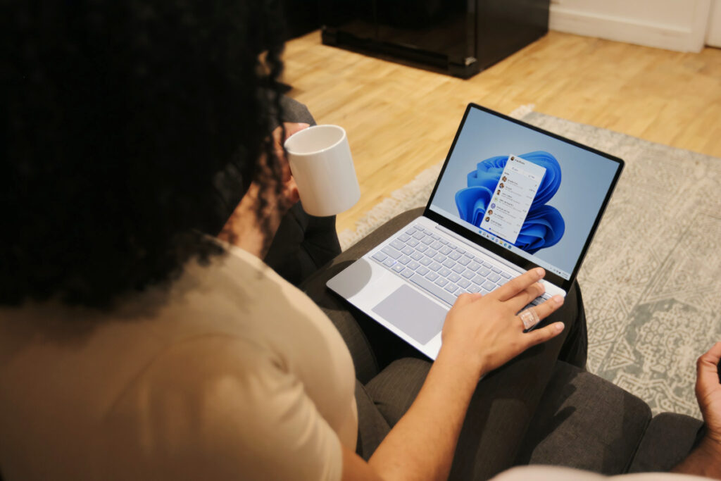 Una persona usa una laptop con Windows 11 mientras bebe una taza de café.