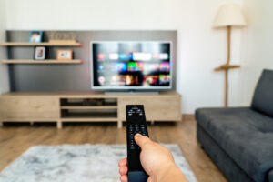 Persona con un control remoto apuntando al televisor en una casa.