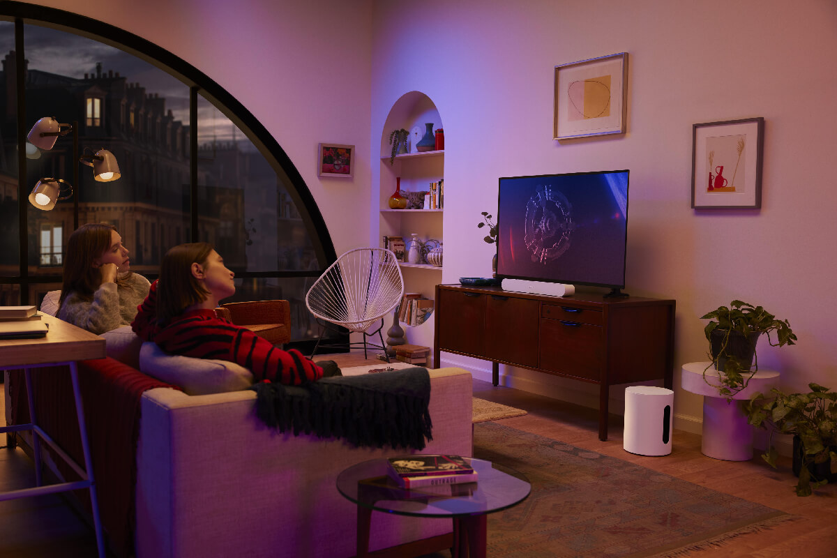Dos personas viendo contenido multimedia en su televisor con el Sub Mini de Sonos.