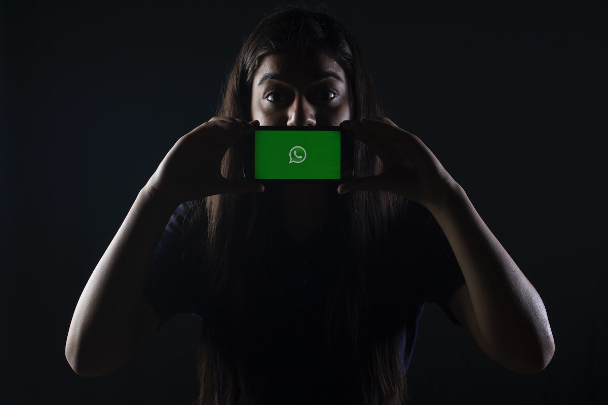 Una mujer sosteniendo un celular con el logo de WhatsApp.