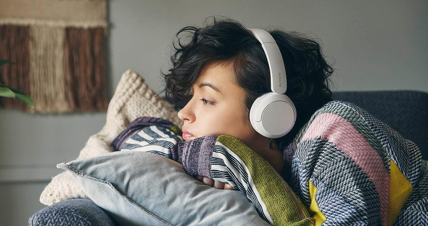 Mujer escuchando música mediante unos audífonos inalámbricos de Sony. 